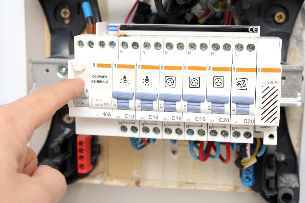 électricien pointant un interrupteur général sur un tableau de distribution électrique, en cours de vérification ou de dépannage